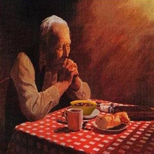 پیرمرد سر میز غذا در دعا کردن و غذا خوردن