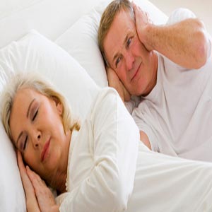 مرد و زن مسن بر روی تخت زن در حال خر و پف و دستهای مرد بر روی گوشهایش